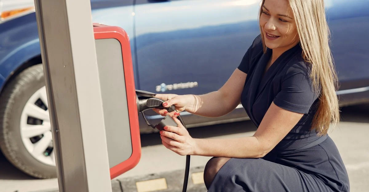 Une femme charge joyeusement sa voiture électrique à une station, contribuant à un mode de vie écologique.